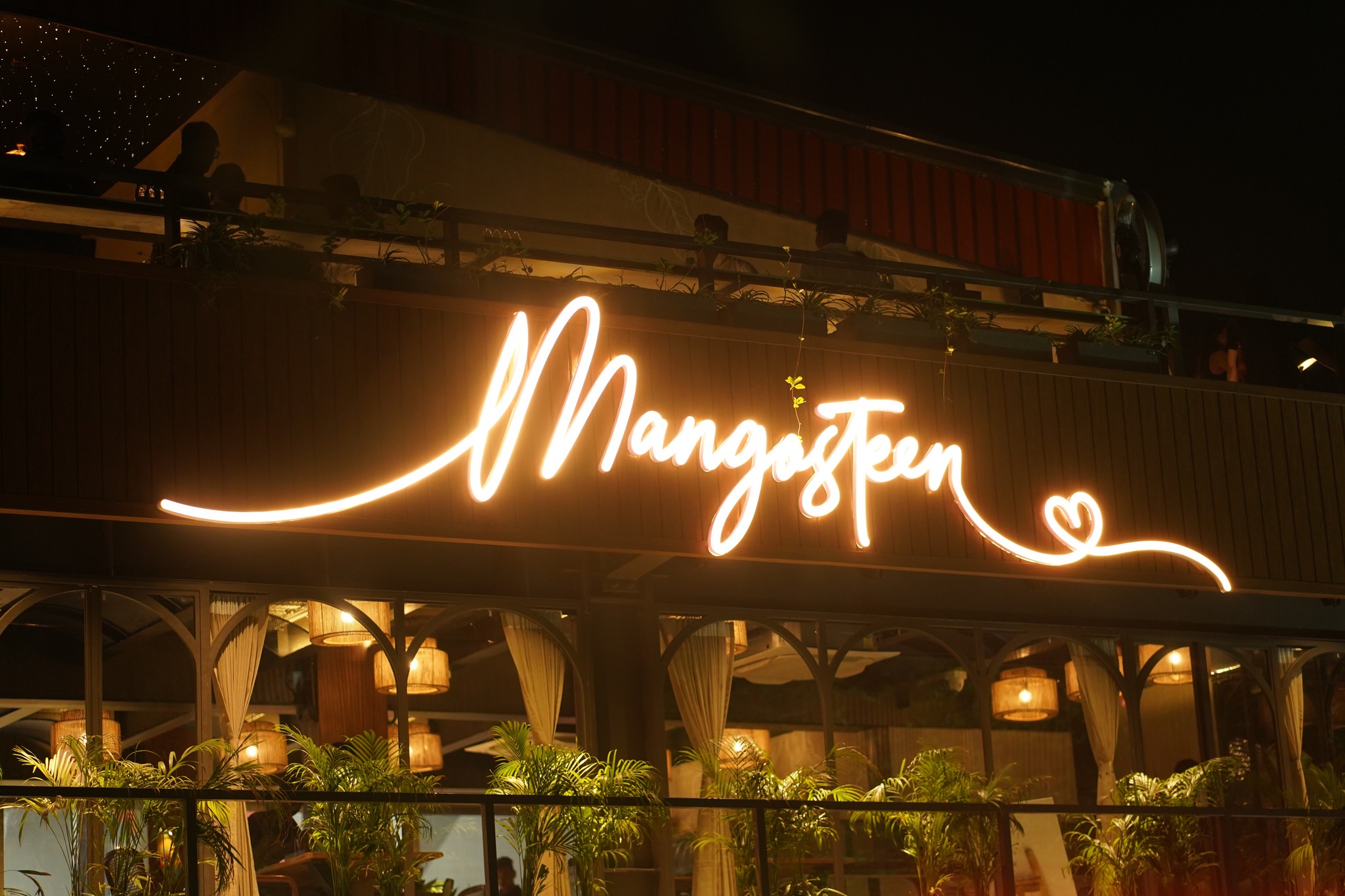 Mangosteen Cafe neon sign on lush exterior